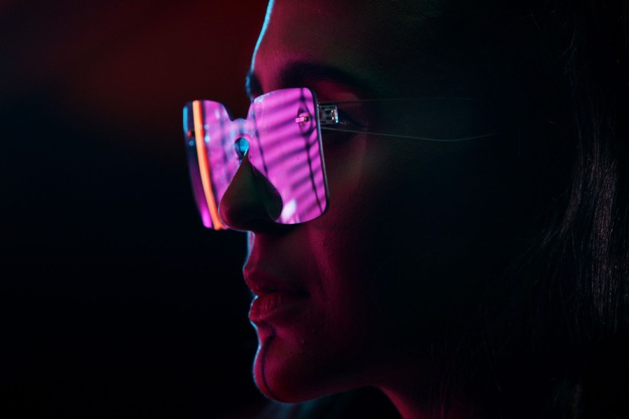 A person is seen wearing glasses in a purple light.