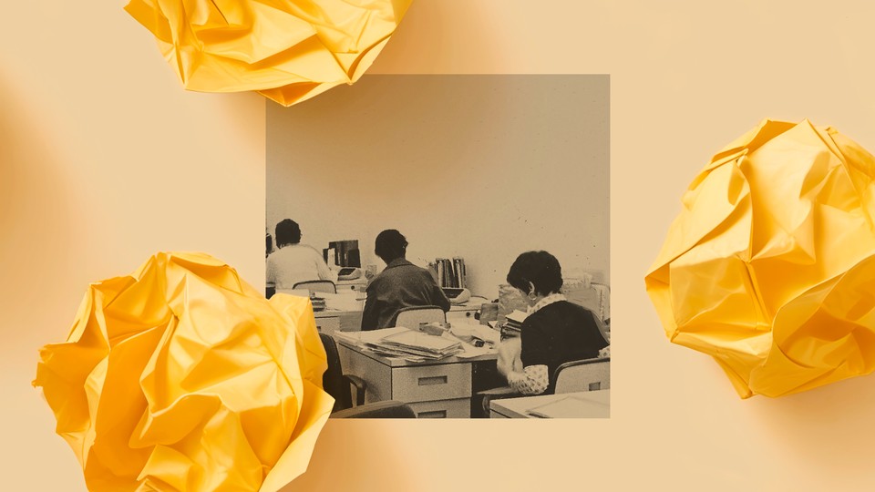 A black and white photo shows three desks in a row inside an office. A woman sits working at each desk