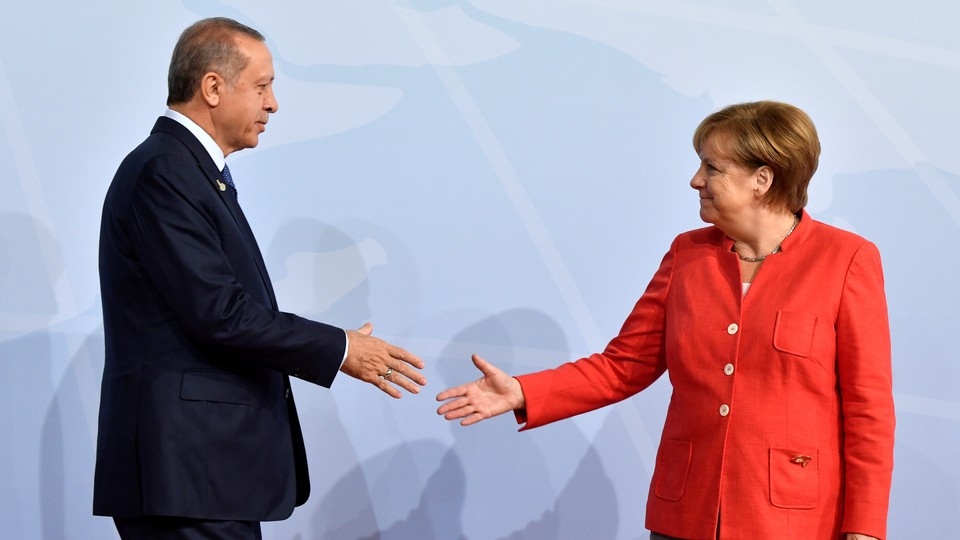 German Chancellor Angela Merkel greets Turkey's President Recep Tayyip Erdogan shake hands on stage at the G20.
