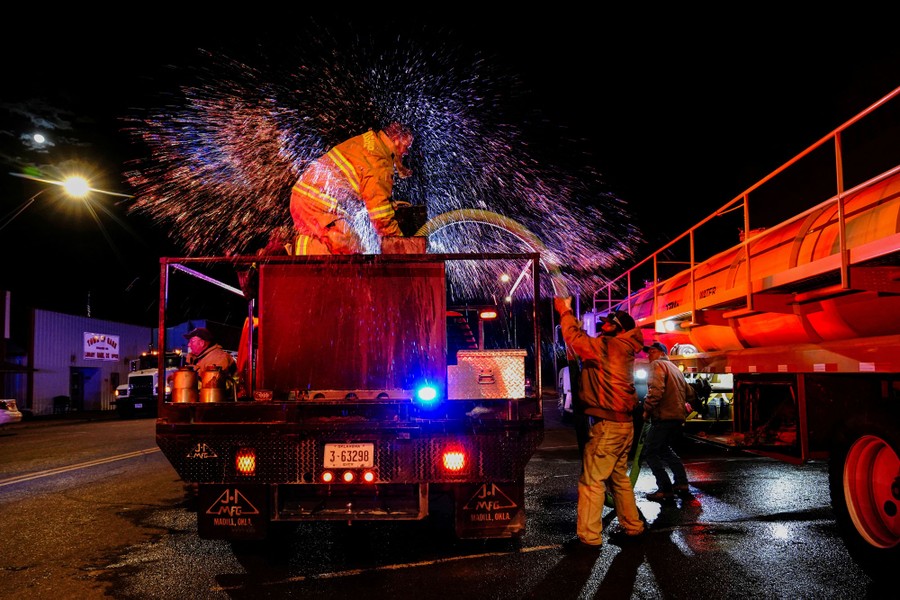 Firefighters refill a pumper truck at night.