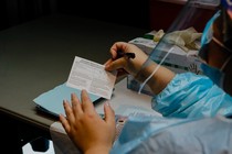 A doctor fills out a vaccination card