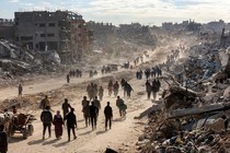 Photo of people walking past rubble in the Gaza Strip