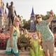 A family wearing masks takes a selfie in front of the statue of Walt Disney and Mickey Mouse at Disney World.