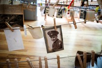 Old photographs hang from clothespins on lines on inside a gymnasium.