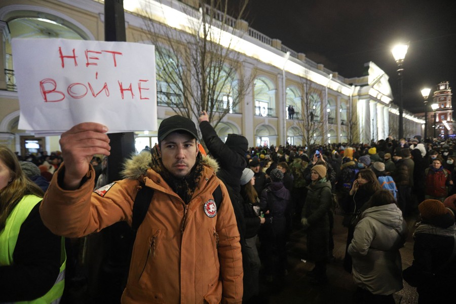 A person holds a placard reading "no war" in Russian, during a larger protest.