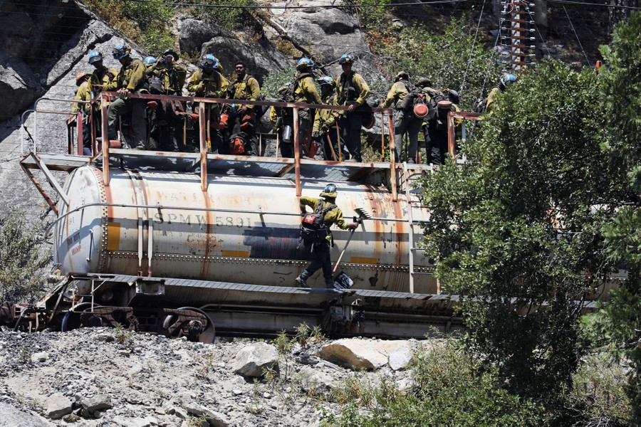 Firefighters ride on a rail car.
