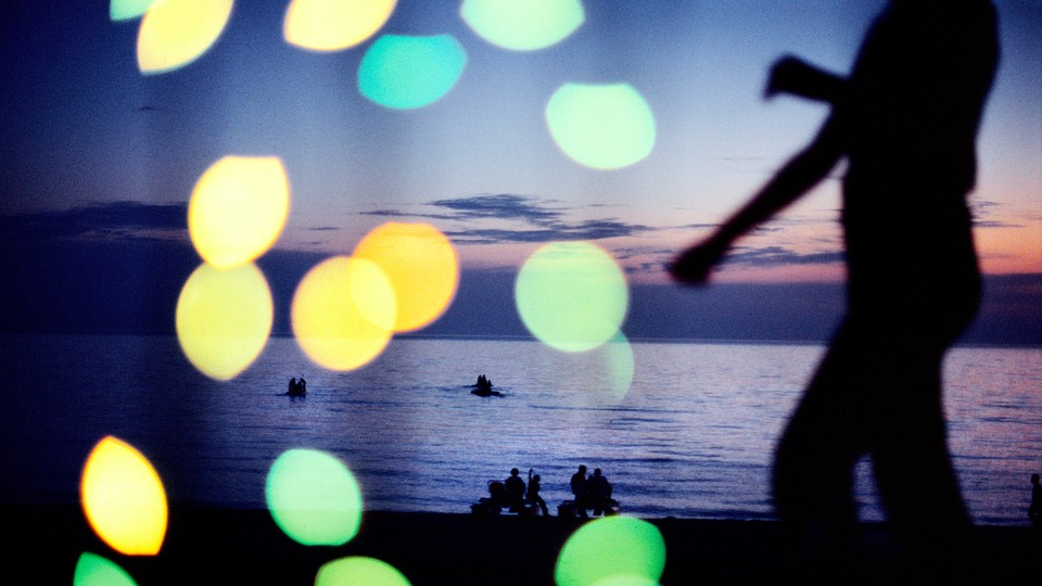 A silhouette of a person in front of a body of water at sunset