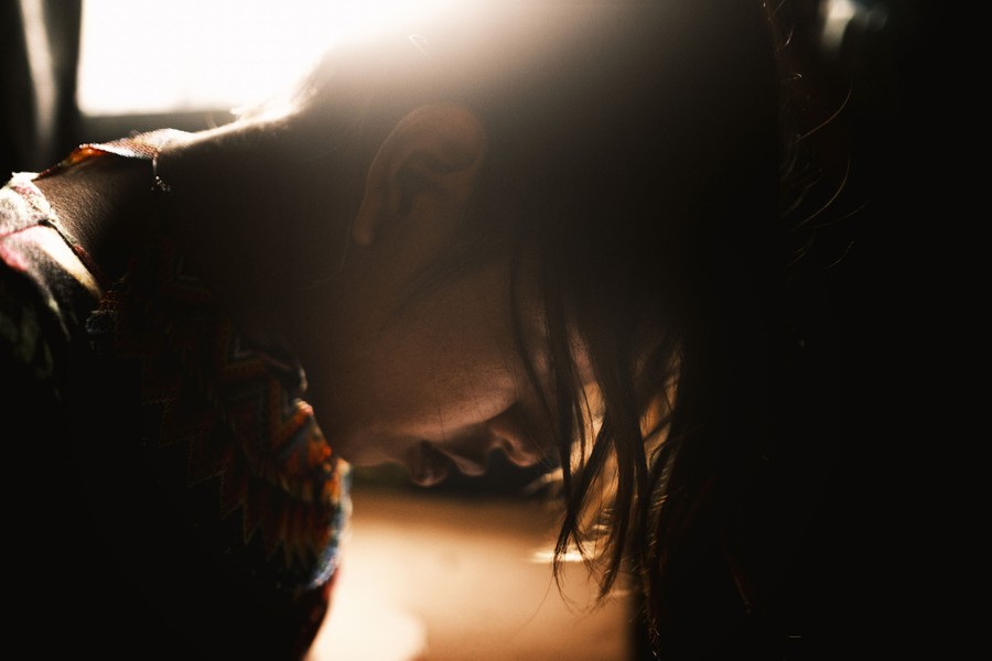 A close view of a woman leaning forward, backlit by soft light