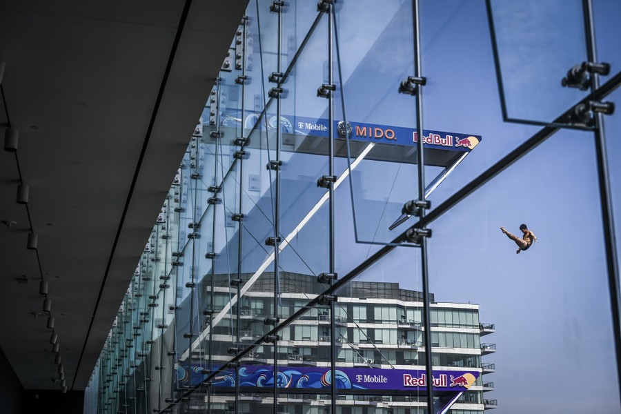 A diver is seen mid-jump, leaping from a platform set up on the roof of a building.