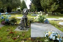 Gravestones, flowers, and a statue of a dog