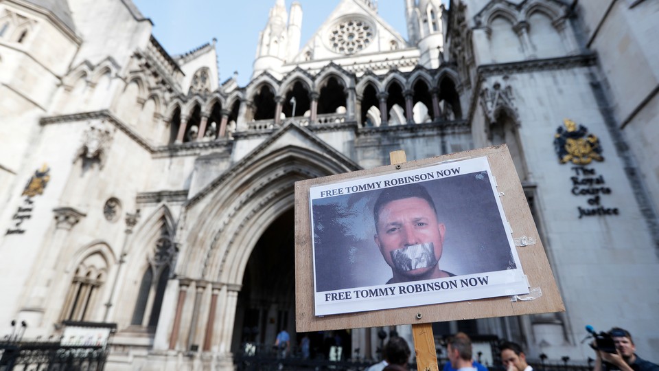 Protesters hold up a placard saying "Free Tommy Robinson Now" outside the Royal Courts of Justice in London on August 1, 2018
