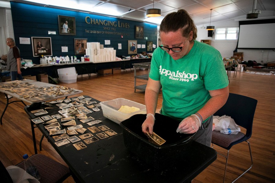 A person works in a schoolroom cleaning damaged old photographs.