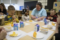 A  diverse group of children eats apples and drinks milk.