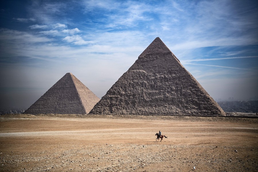A man rides a horse past the pyramids near Cairo.