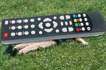 A person lying on the ground under a huge remote
