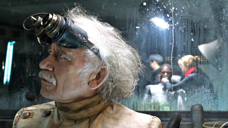 A scientist with binoculars in front of a man in a facility