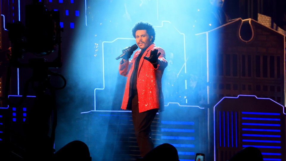 The Weeknd performing at the Super Bowl halftime show bathed in a column of light