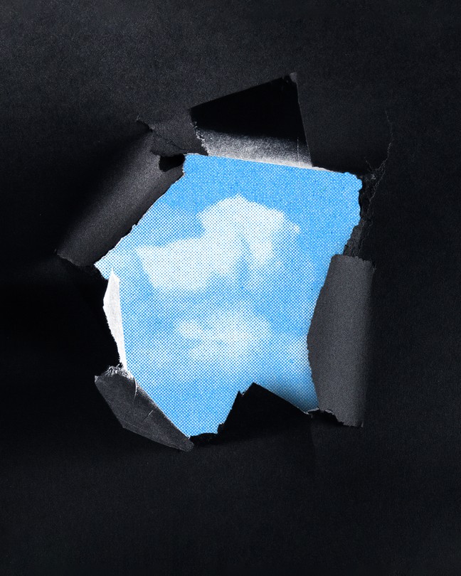 An illustration of a patch of blue sky appearing from behind torn black paper