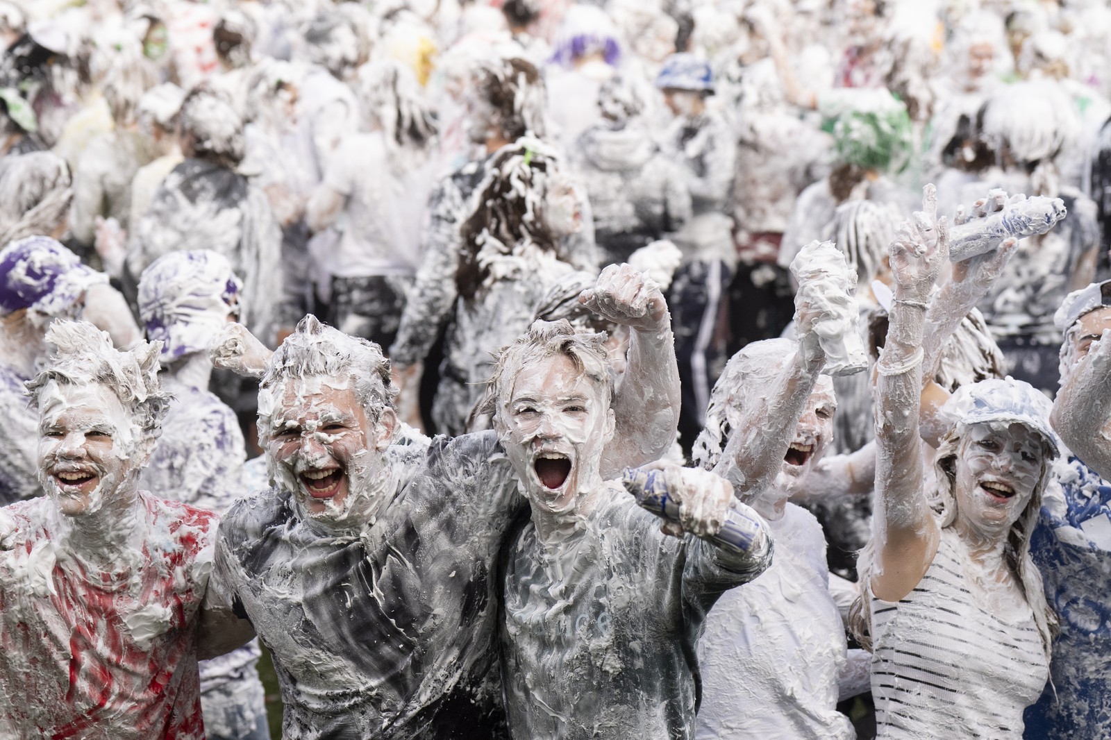 Students cheer and pose while covered head-to-toe in soapy foam.