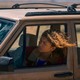 Zendaya as Rue sticks her head out of the driver's side window of a dirty car.
