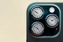 Photo-illustration of close-up detail of smartphone camera with three lenses, each replaced by a round clock showing a different time.