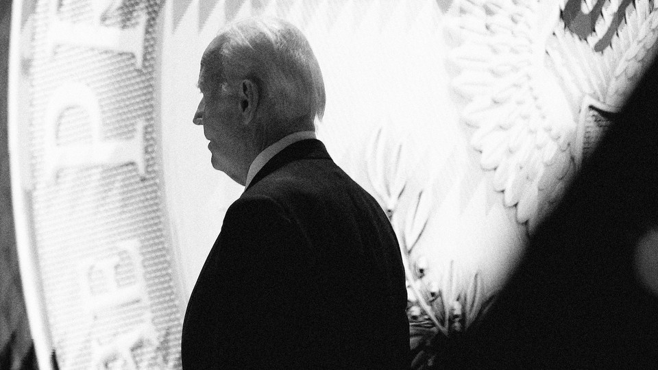 Black-and-white photo of Joe Biden standing in front of the presidential seal