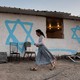 A young woman walks past an Israeli settlers' shack in the newly established wildcat outpost of Eviatar, near the northern Palestinian city of Nablus in the occupied West Bank, on July 1, 2021.