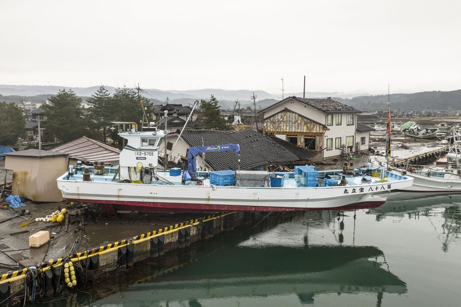 A commercial boat rests on a dock after being washed ashore.