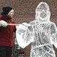 A woman raises an ice-scraping tool next to an ice sculpture of Jesus Christ.