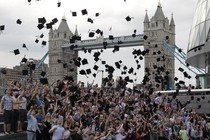 Students toss graduation caps in the air in front of London's Tower Bridge.