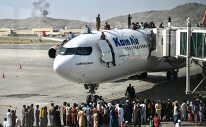 Afghan citizens climbing atop a plane at Kabul airport.