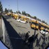 A parking lot filled with school buses is reflected in a bus mirror 