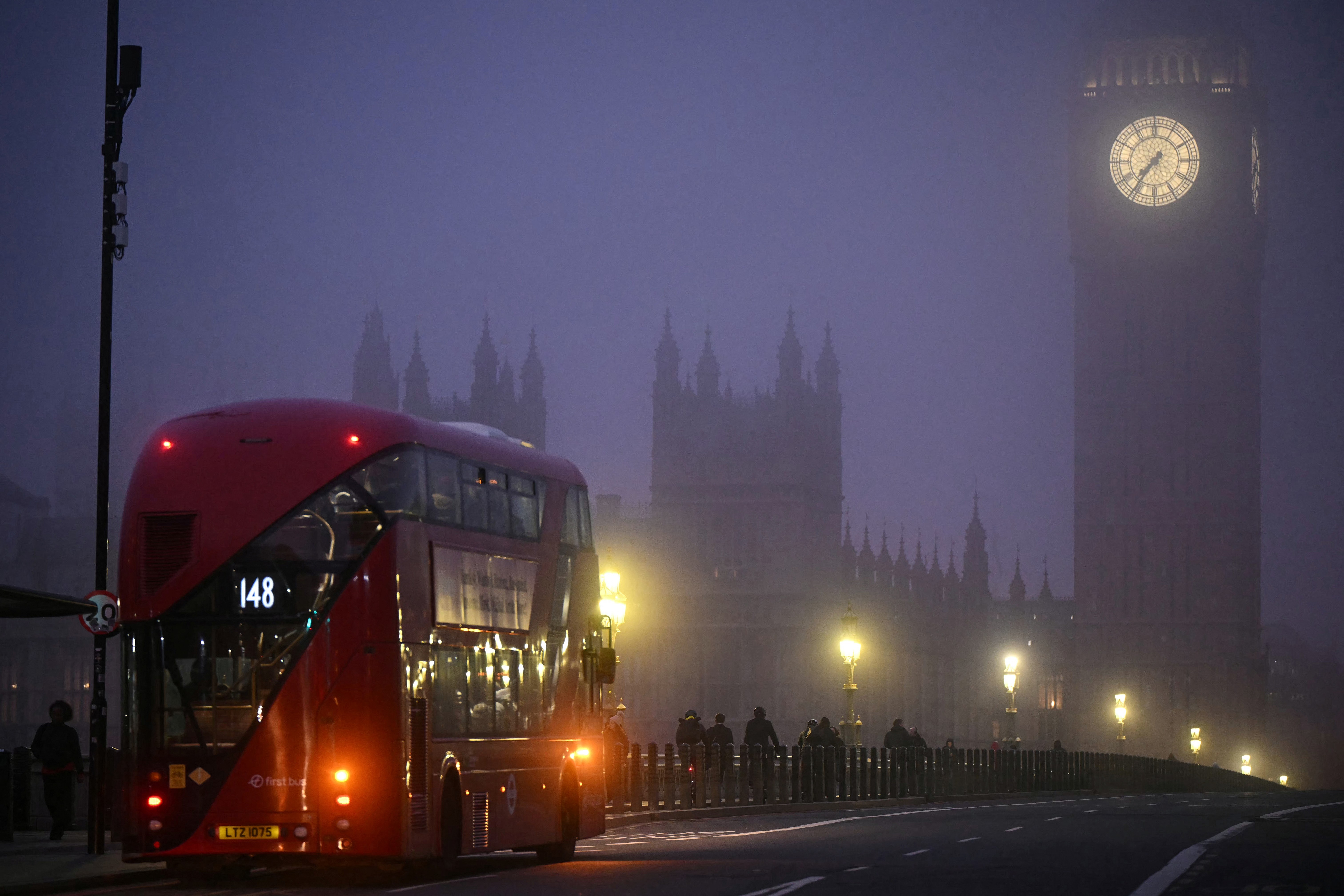 A double-decker bus crosses Westminster Bridge as fog covers the streets of London.