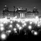 A black-and-white photo of protesters holding up lights outside the Reichstag building