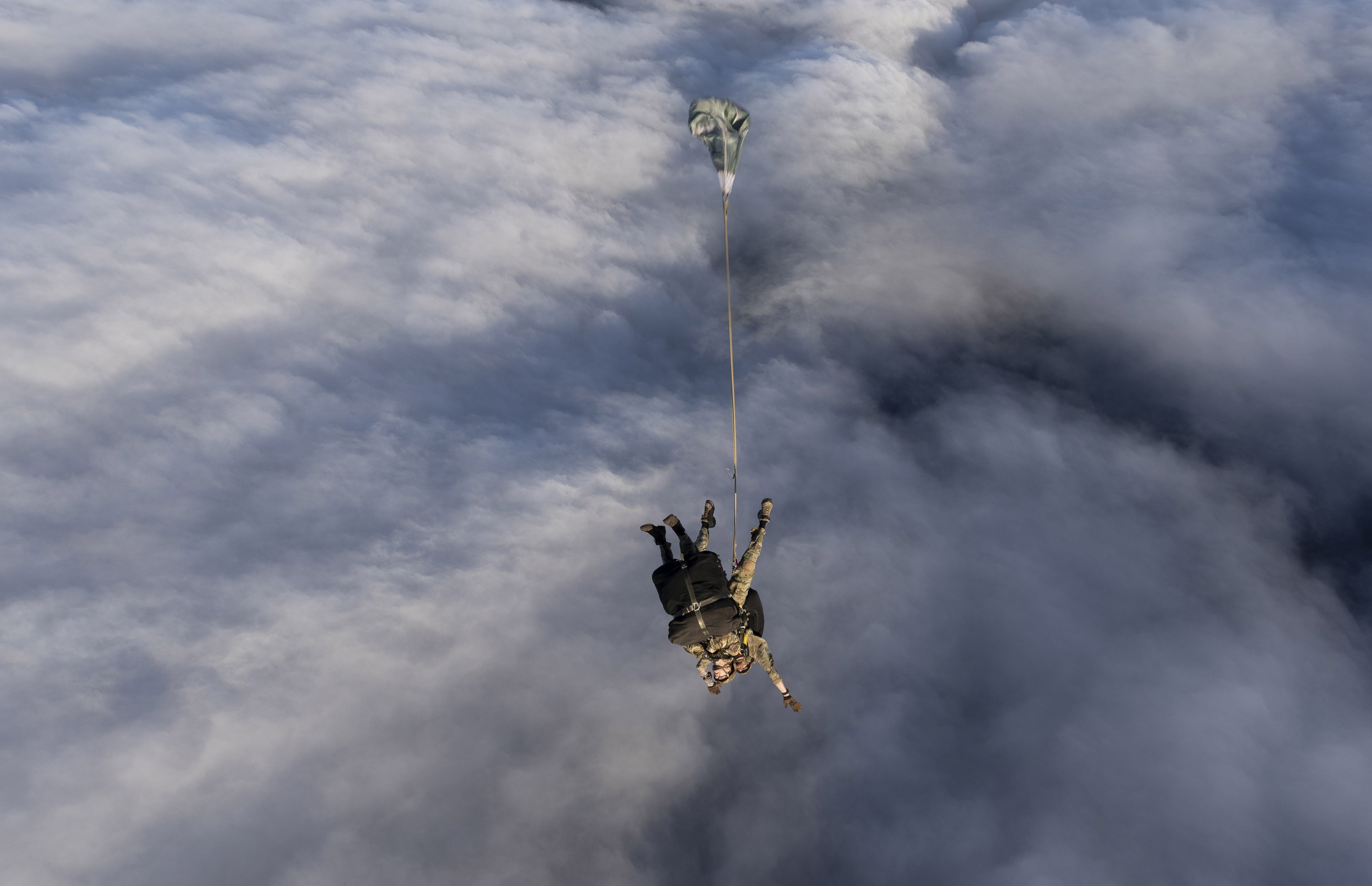 A view, looking down, on two tandem parachutists who have just jumped from an aircraft.