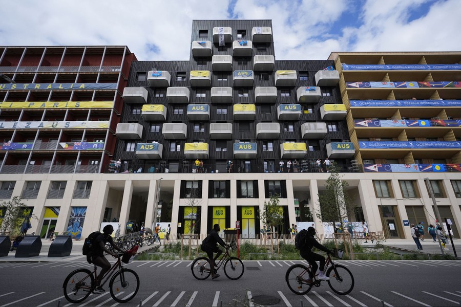 People ride bicycles in front of the Team Australia residence in Paris.