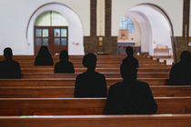 Church pews with black silhouettes of congregants