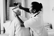 A health aide helps comb the hair of an elderly person