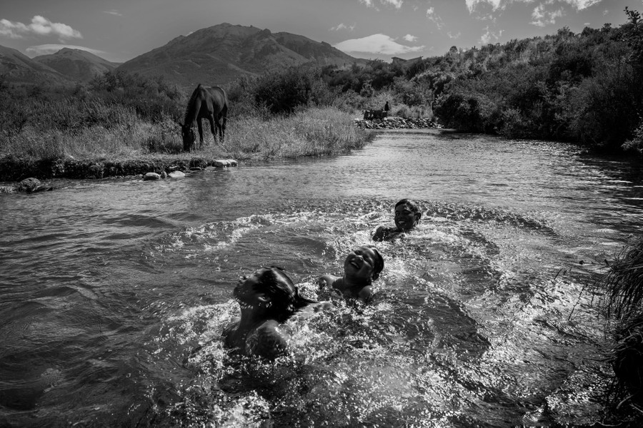 Several young people swim and play in a river.