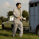 A movie still of Sacha Baron Cohen next to an animal trailer