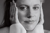 Black-and-white portrait of Greta Gerwig, with her hands cupping her face