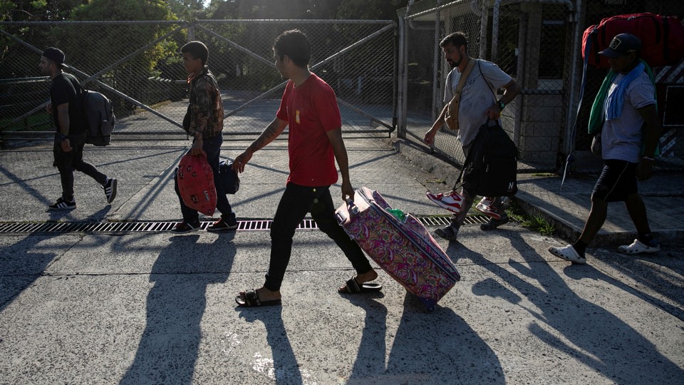 A photograph of migrants walking with suitcases
