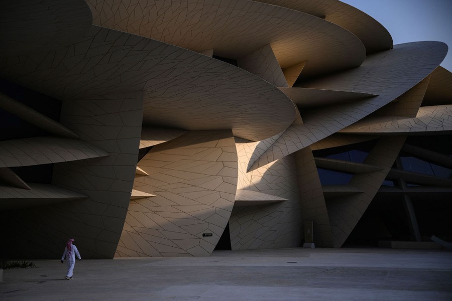 A person walks beside a building that appears to be constructed out of massive intersecting discs.