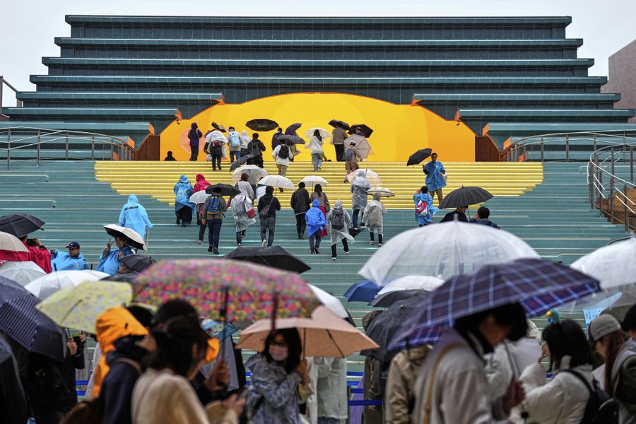 People climb stairs into the arched entrance of a pavilion.
