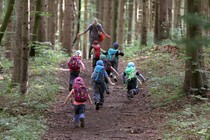 Kids with backpacks running up a forest trail