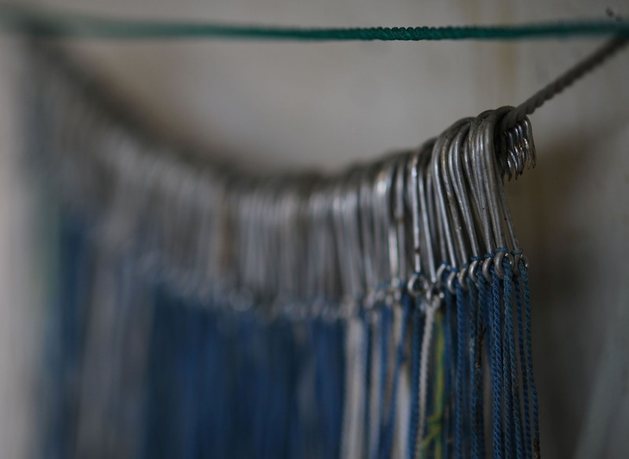 Many fish hooks hang from a line inside a building.