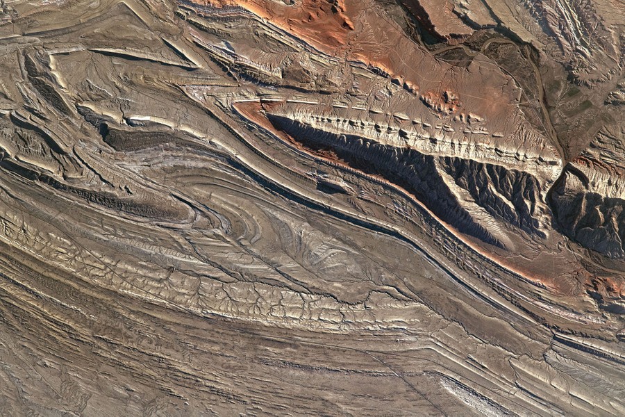 Twisting and striated landforms are seen in a high desert.