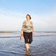 Ewine van Dishoeck wades in the water at Noordwijk beach while holding her shoes.