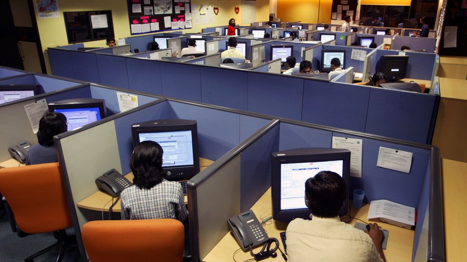Office workers sit at cubicles in a call center