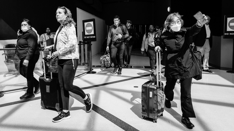 .Travelers disperse as they exit a section of an airport.